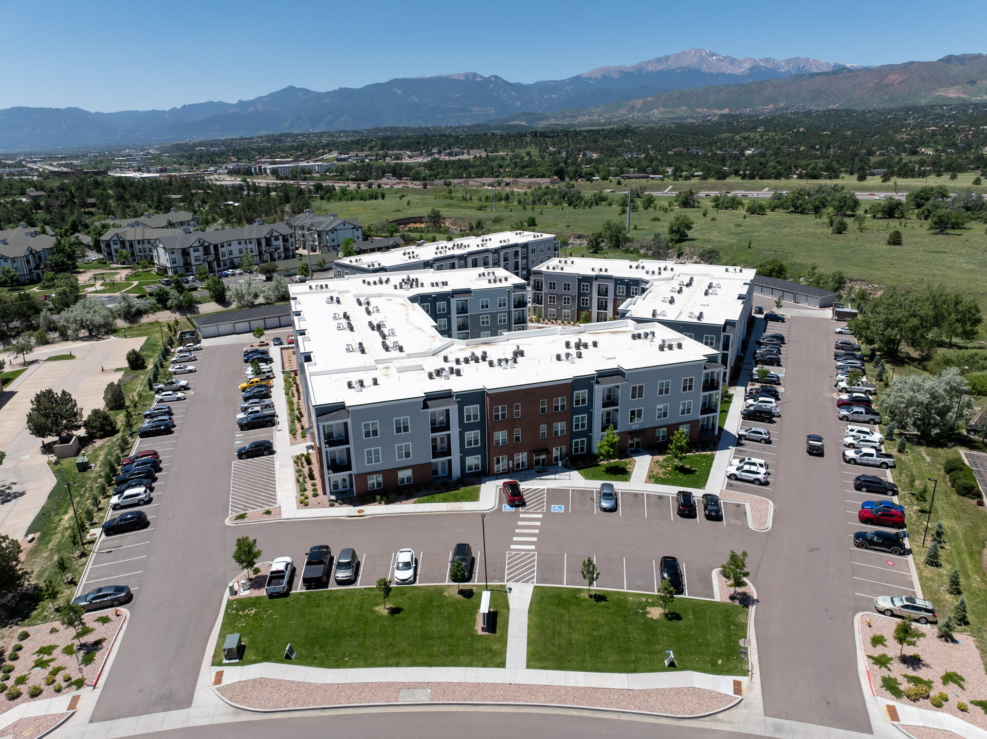 Aerial view of a multifamily residential community with Pikes Peak and the full Front Range as backdrop, Colorado Springs