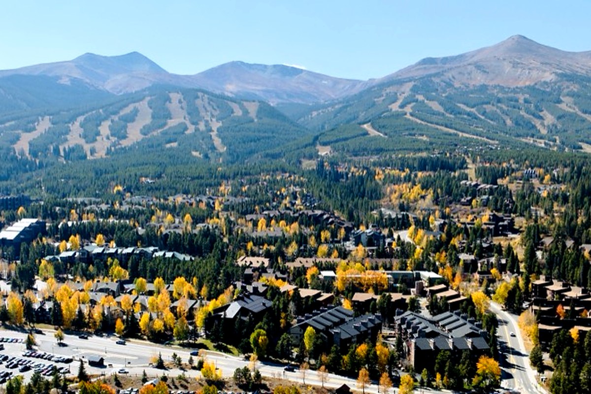 Aerial view of Breckenridge in peak fall foliage with ski runs on the mountain behind