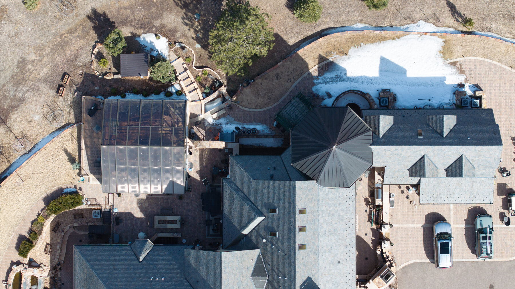 Nadir aerial view of a complex estate roof — multiple planes, standing seam metal turret, solar panels, and skylights documented in a single flight