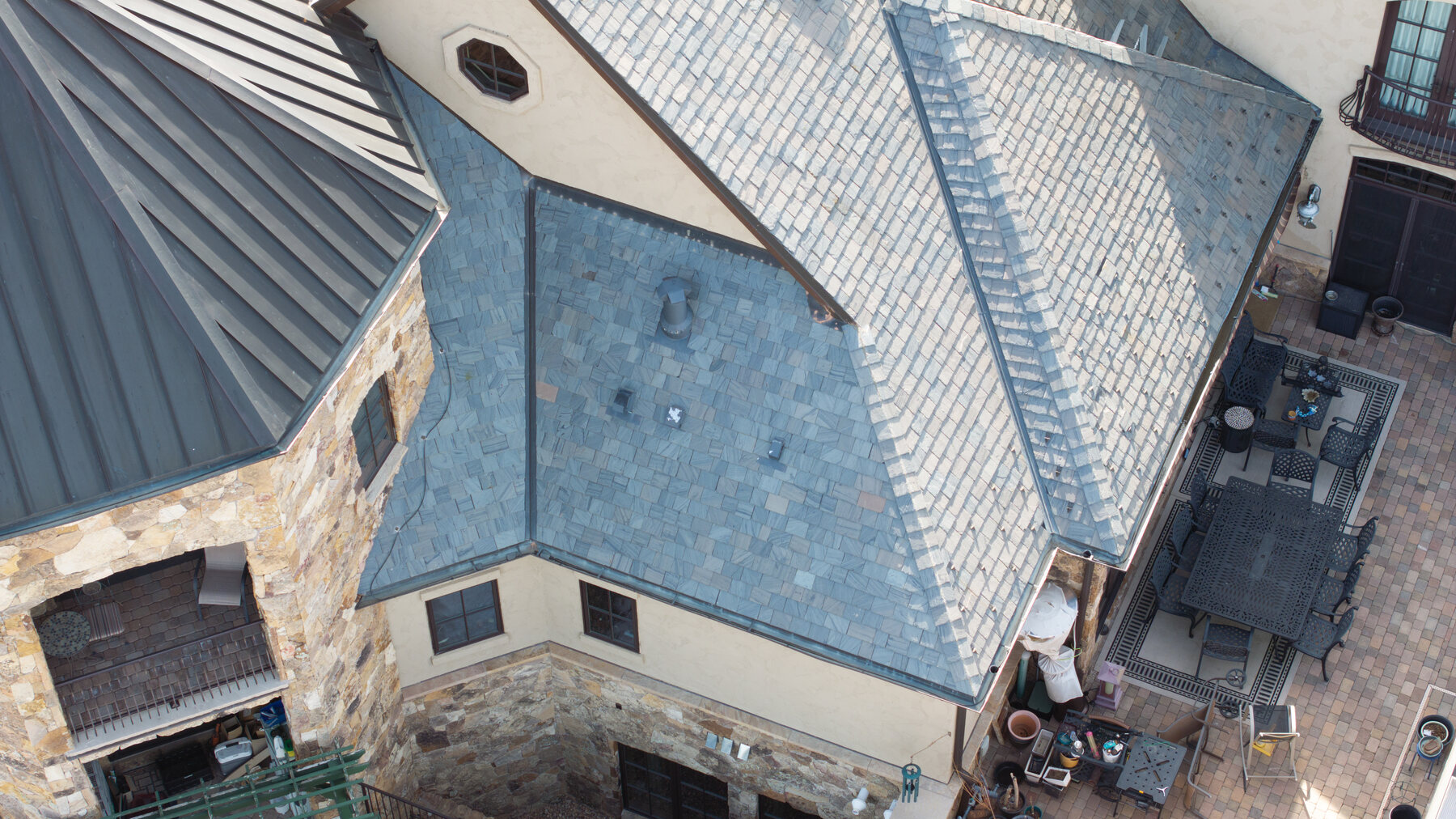 Valley where two steep slate planes meet — pipe penetration, standing seam transition, and skylight flashing all documented in one frame