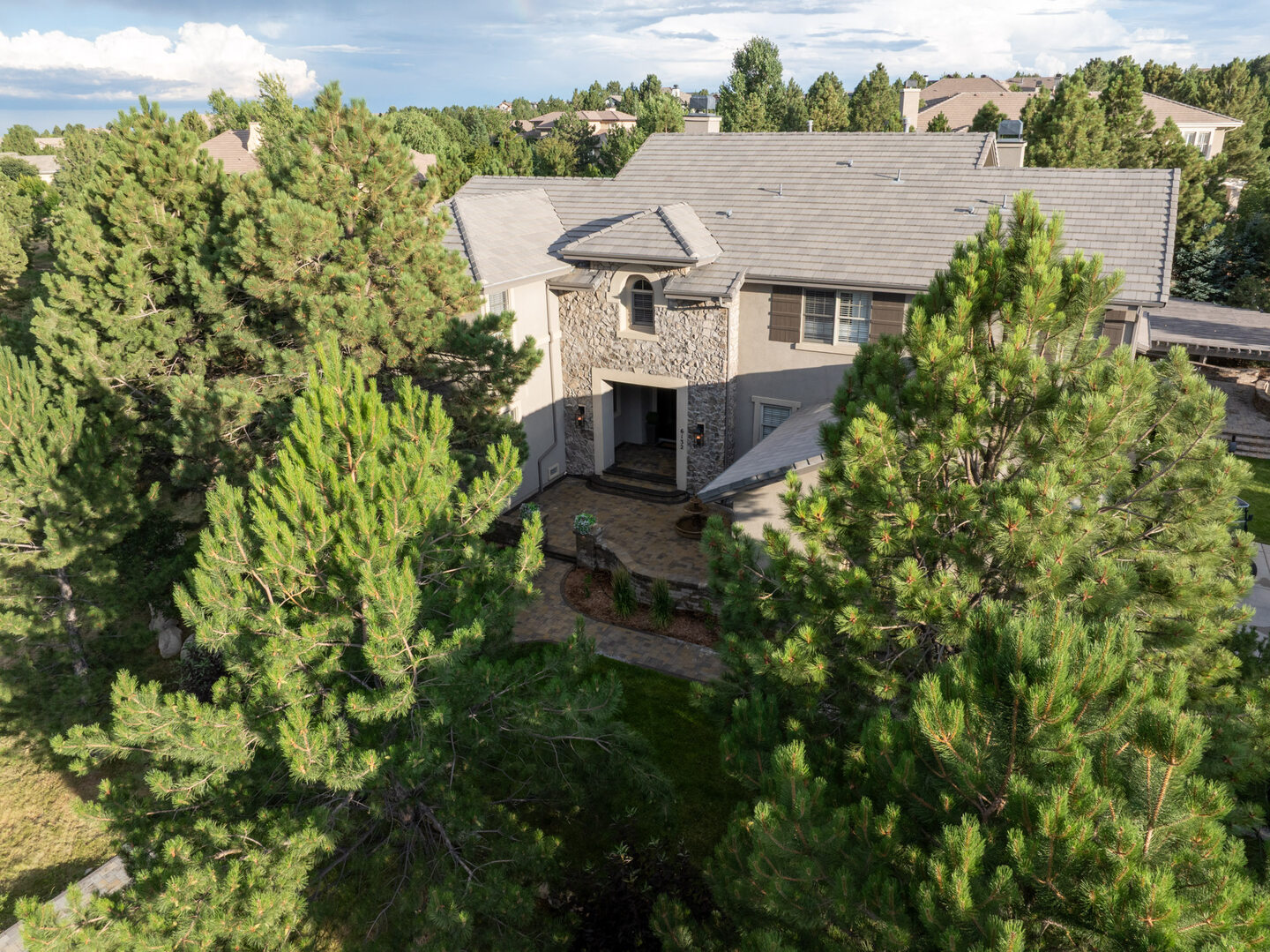 Aerial view of a stone-facade estate home nestled within mature Colorado pines