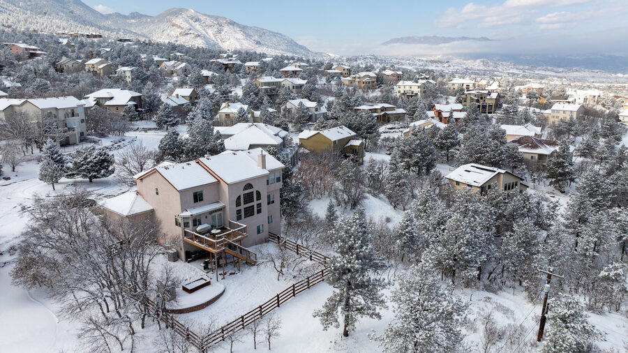 Winter aerial view of a luxury Colorado Springs neighborhood blanketed in snow with Cheyenne Mountain